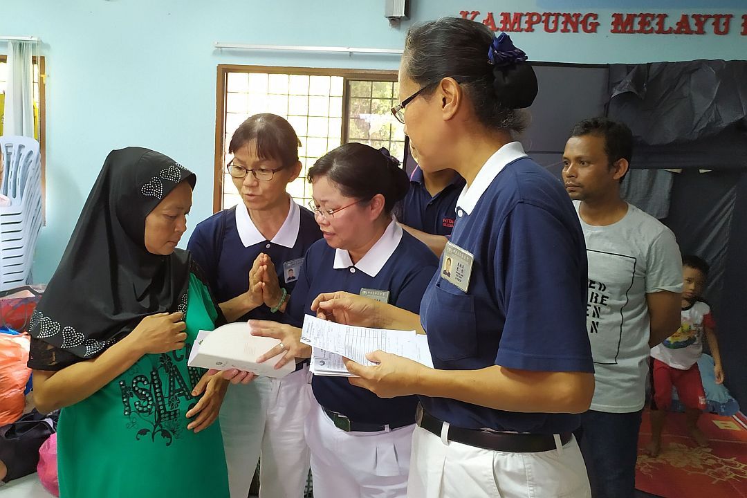 Tzu Chi volunteers disbursed relief cash to the fire victims. [Photography by Ong Seng Yeow]
