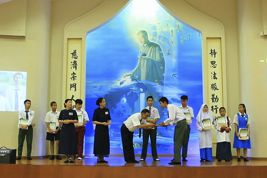 慈济亚庇支会负责人张植青（左）颁发奖励金及奖状予学生。 【摄影：吴勇樻】