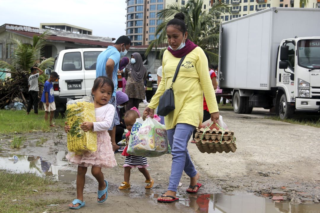 发放后，村民偕同孩子提着物资回家。 【摄影：谢念祥】