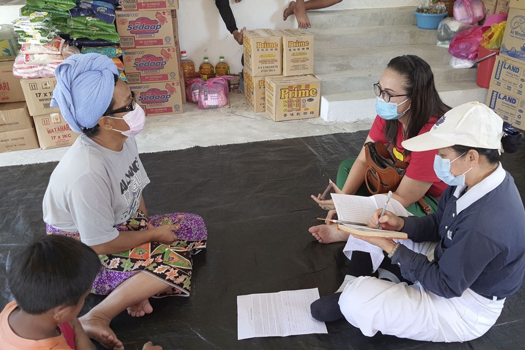 志工徐慧芳在教堂内关怀灾民乌列（左），苏西丽雅（红衣者）在旁协助翻译，加速探勘的工作。 【摄影：陈玉娟】