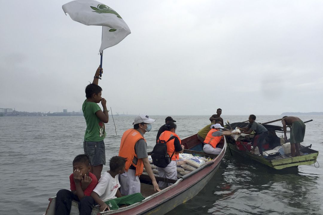 船上的巴夭族小孩扬起慈济旗，迎风招展，志工前往为拿笃无国籍水上人家送物资。 【摄影：陈文忠】