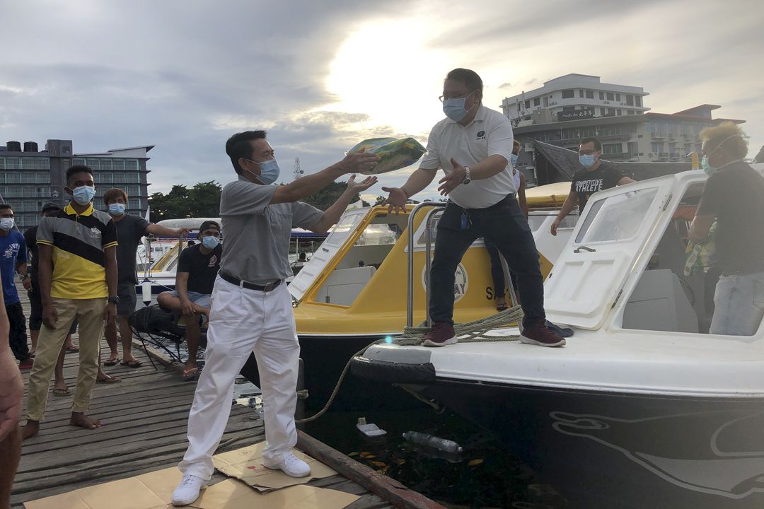 王殿祥医生（右）与志工张赐君合力将物资搬运到快艇，准备发放给岛民。 【摄影：沈萍萍】