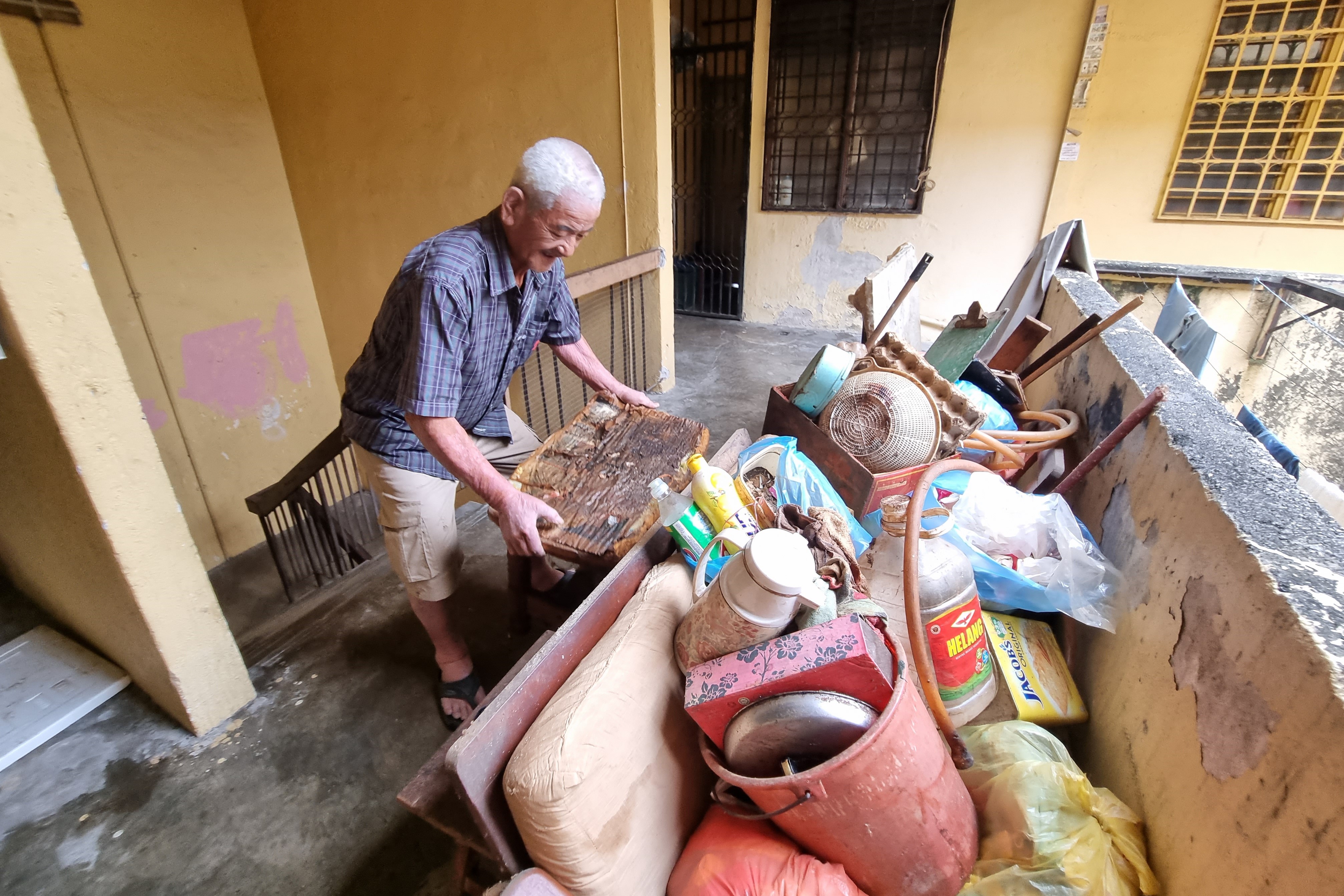 黄旺友阿公一早先将要丢弃的木沙发、物品、用具先从屋里拖到外面走廊旁，方便志工搬运下楼。【摄影：陈泛全】	  