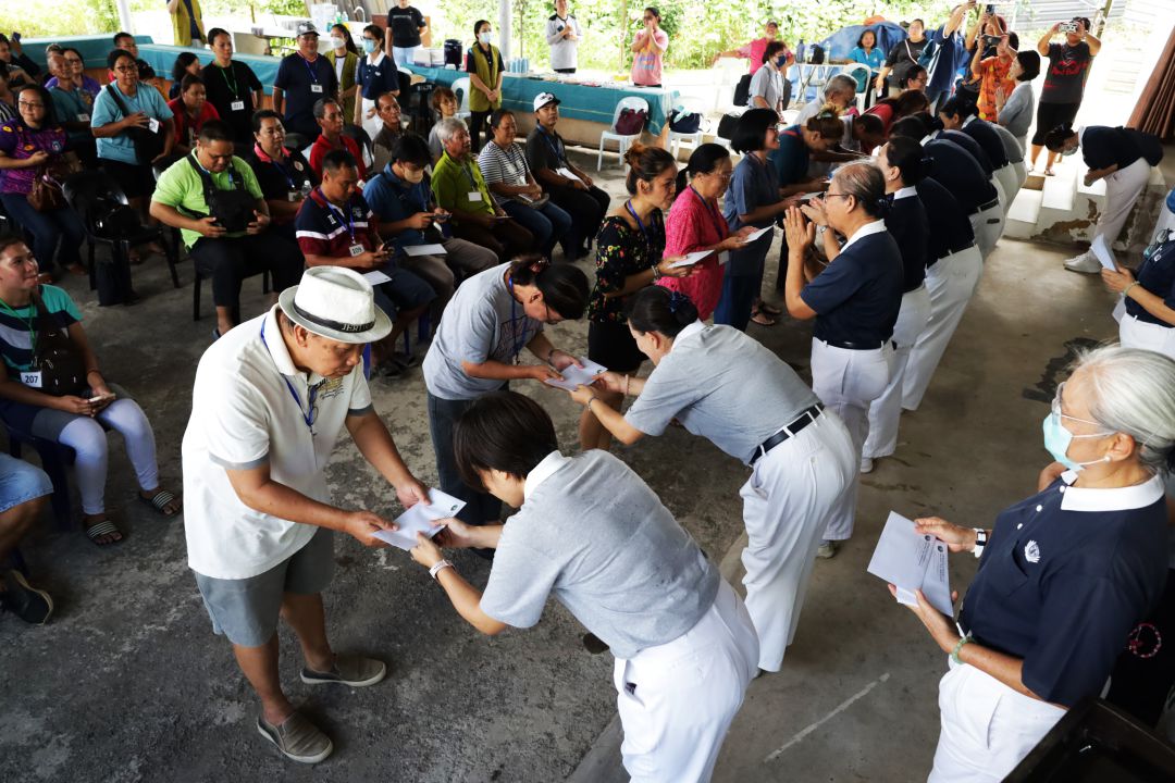 志工恭敬地把应急金递给灾民。【摄影：郭浩然】