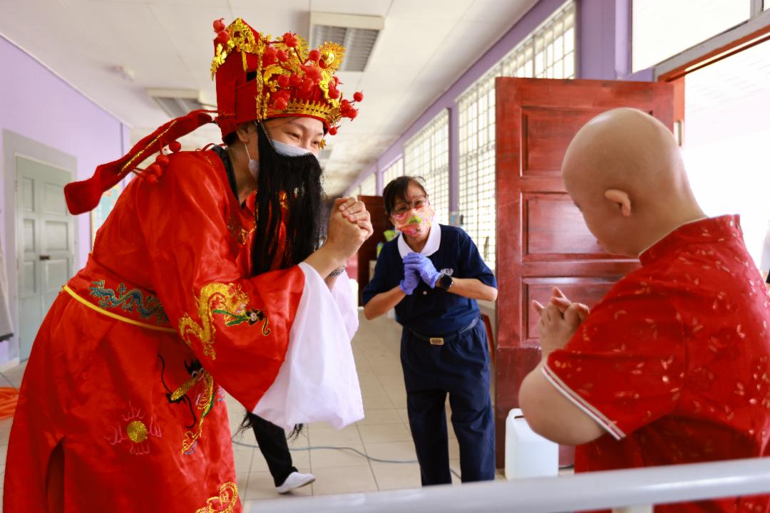 志工邱秀玲化身为财神爷，向病友送上祝福，病友欢喜收下祝福。【摄影：梁倩宜】	