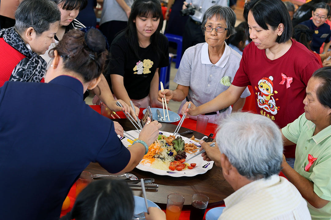 吴桂雯（红衣者）参与慈济为照顾户举办的新春发放活动，与众人欢喜迎新年。【摄影：罗秀娟】
