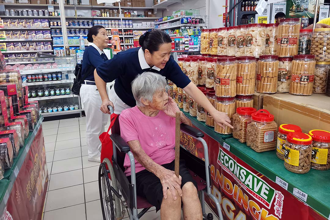 志工贴心陪伴，照顾户开心采买年货。【摄影：郭丽仪】