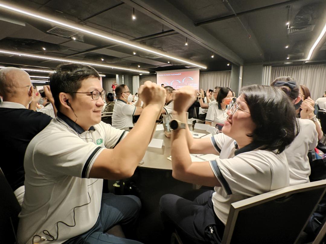 两人合作的击掌活动到全体一起协调节奏，共同完成击掌动作。中学化学老师朱声勇(左)，既是学员也是同仁营总协调；完成协调工作的同时也不错过培训活动。 【摄影：刘玉丽】