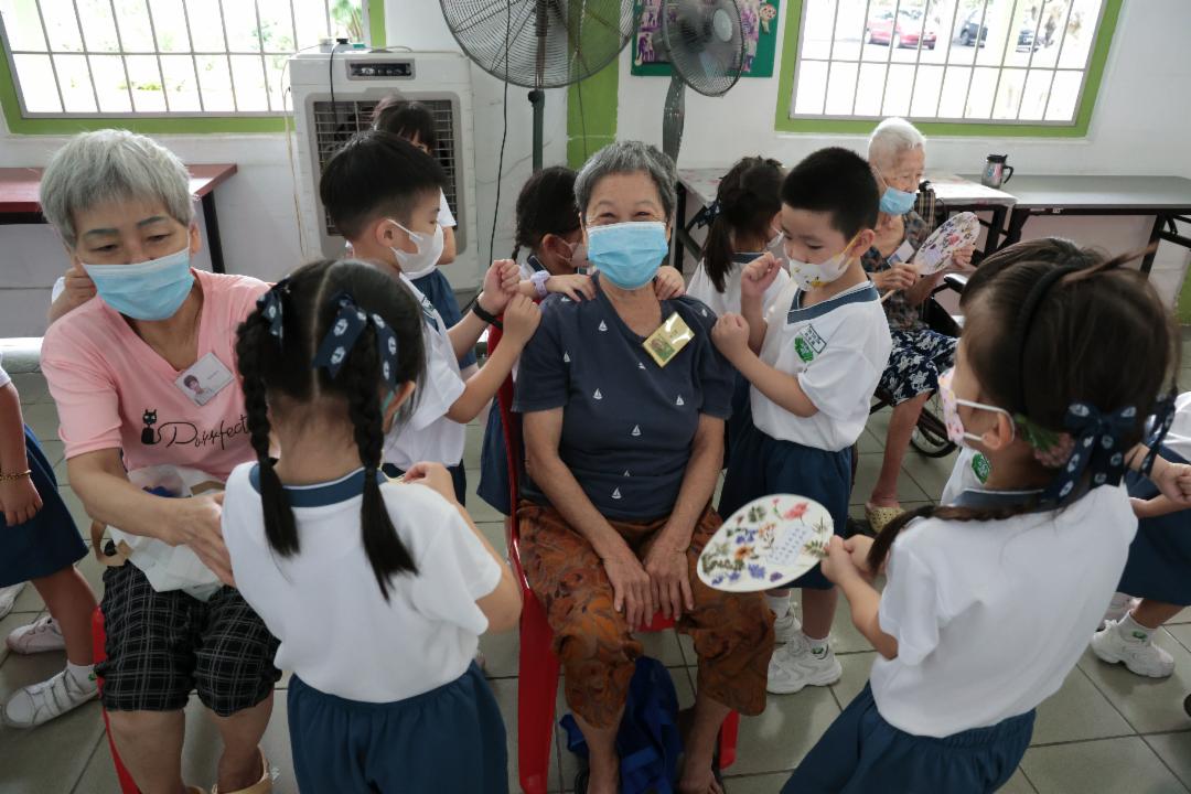 孩子们分工合作，卖力地为阿嬷按摩、捶背，有的还贴心地扇风，逗得阿嬷笑开怀。 【摄影：黄莉燕】