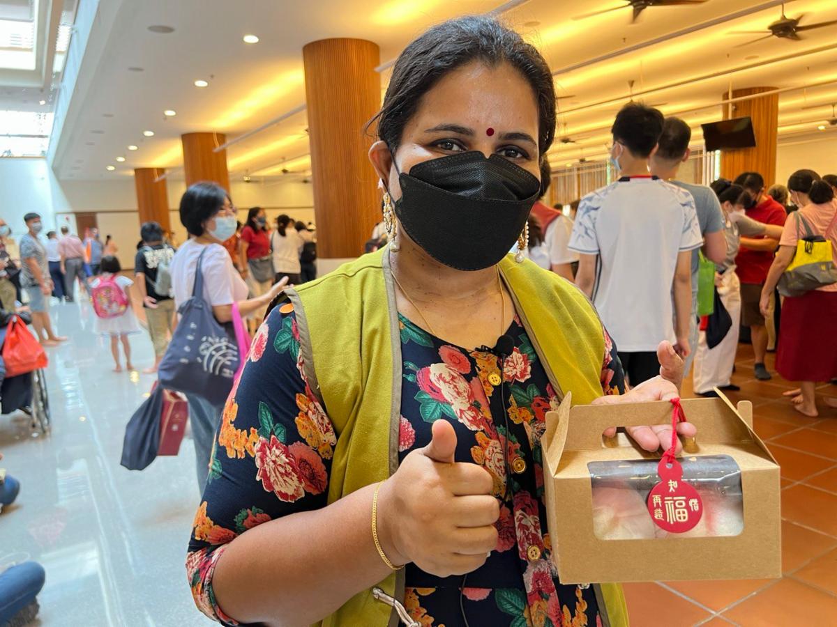 Lalitha is grateful for the opportunity to give. She gave a thumbs up receiving the peach buns from volunteers. [Photo by Ngeu Yet Fatt]