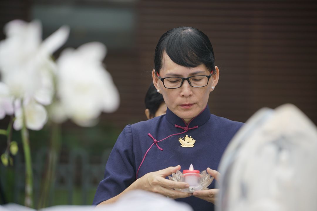 在浴佛的献供队伍里，邱绿育手捧灯烛，默默地在心中为儿子祝福。 【摄影：文伟光】