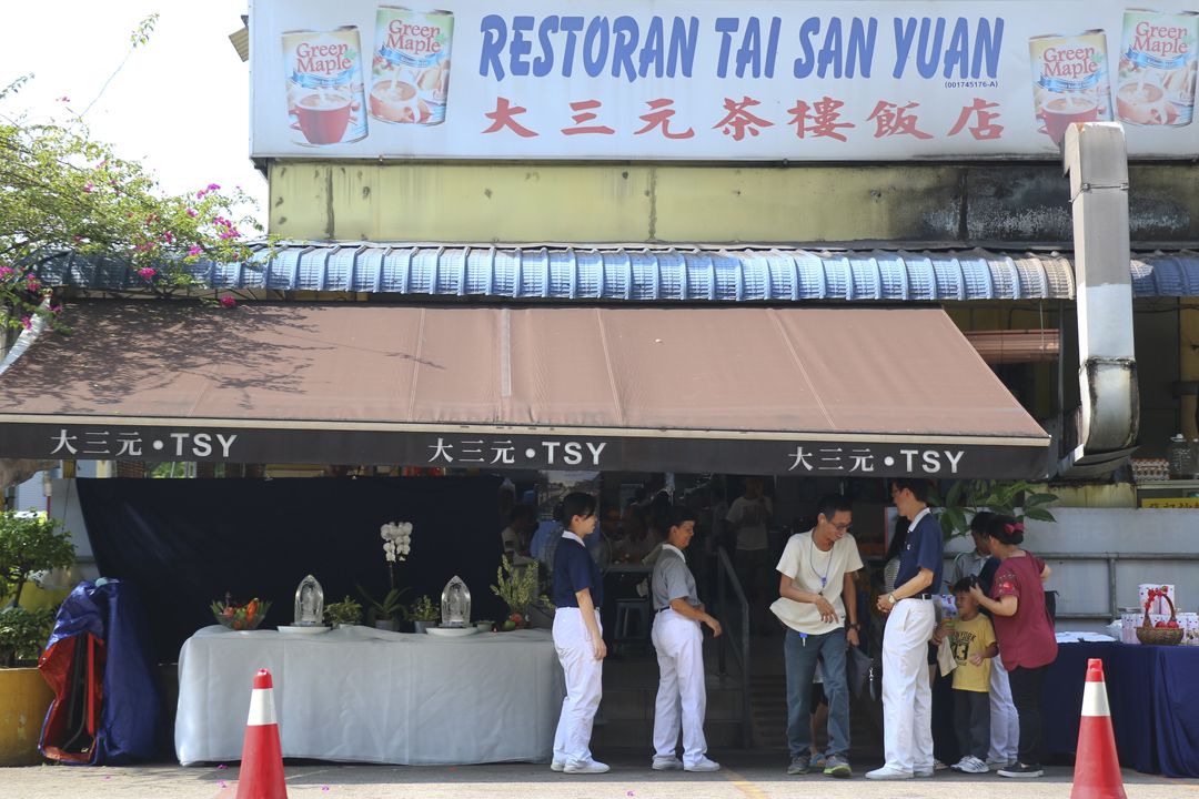 庄严朴实的浴佛台设置在大三元茶楼饭店前，接引附近的居民、工作人士、小贩和顾客前来参与流动浴佛。【摄影：何赞文】