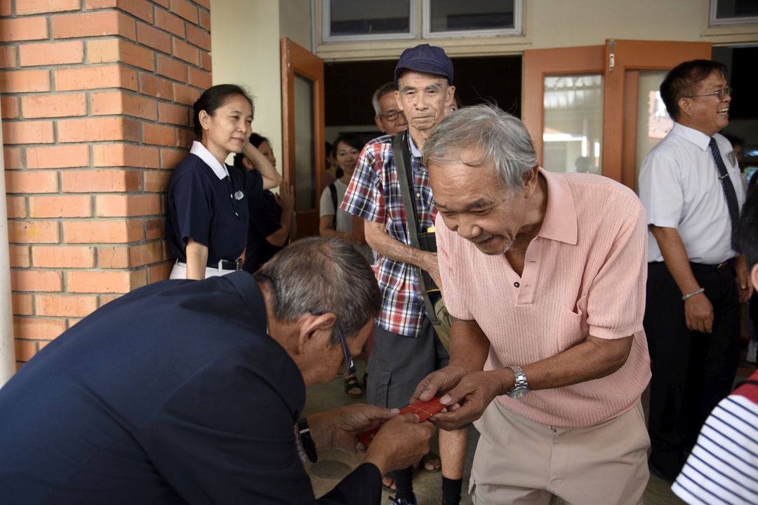 慈济亚庇支会负责人张植青恭敬地把福慧红包递参与岁末祝福的民众。 【摄影：翁综徽】