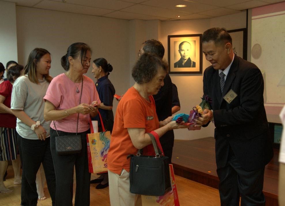 慈济淡属负责人陈家文送上有缘卡和结缘品给会众，把上人的祝福带回家，展开美好的一年。【摄影：赵彩欣】