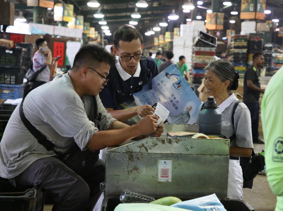 志工无处不在，走入菜市场，传递“报佛音”佳讯。 【摄影：颜锦源】