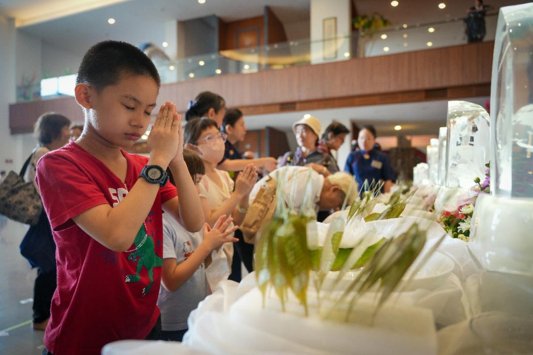 卫塞节当天，不少家庭携老扶幼前来浴佛。孩童专注合掌礼佛，纯真的身影成为道场中最动人的风景。【摄影：文伟光】