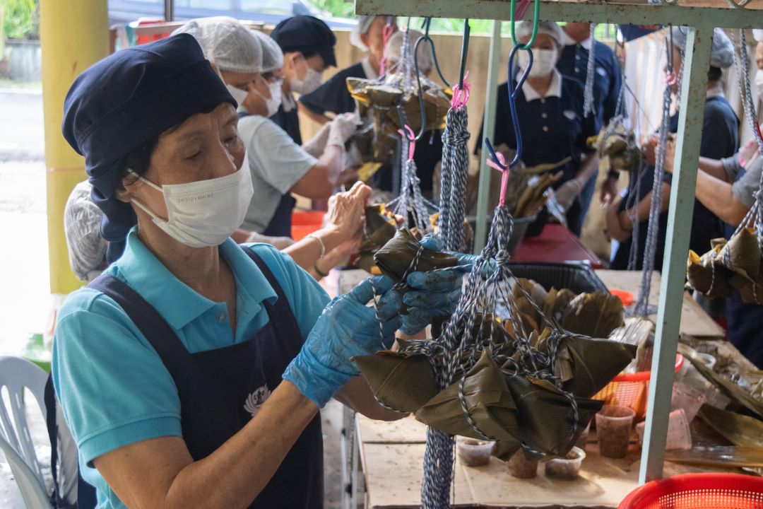 来自淡属百乐县直凉的慈济志工与大众，在欢庆端午佳节之际，首次主办裹素粽义卖活动，借着社区的力量，将爱心化为行动，传送至沙巴州山打根灾区。 【摄影：张国樑】